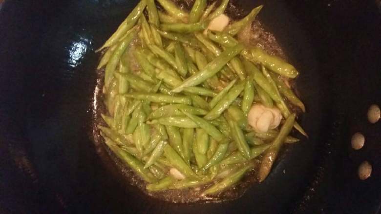 四季豆梅干菜,锅烧热倒入适量色拉油,下蒜蓉炒香加入四季豆煸炒。