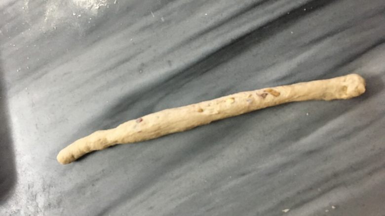红糖枣桃面包,取其中一份，擀成椭圆形，卷长的一边卷起来，搓成细长条