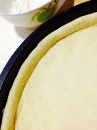 香蕉玉米披萨,披萨盘刷油、放入面皮,手向四周推动着、铺满、边缘呈高檐。