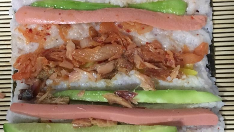 青瓜火腿腊鱼寿司,米饭晾冷后,铺在海苔上面!米饭太热,会把海苔烫软,卷不起来!所以一定要晾冷才能铺!米饭铺好后,就放配料~想吃什么放什么~🤗
