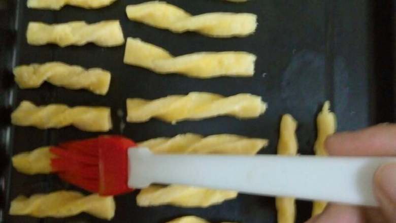 儿童磨牙棒,面团和好后,要用擀面杖杆平,最好别太厚,因为杆面时占着手没法照,然后切成小条,像拧麻花一样,拧一下,烤盘最好铺上油纸(我是懒了才没铺),把拧好的磨牙棒放在烤盘上,刷上蛋液就可以了,可以在刷蛋液前把烤箱预热160度,上下火。