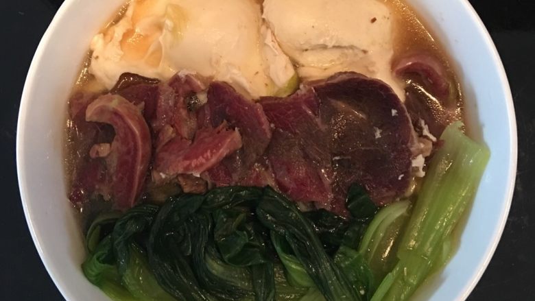 手擀牛肉面,将汤倒入碗中,依次摆上荷包蛋、牛肉、油菜