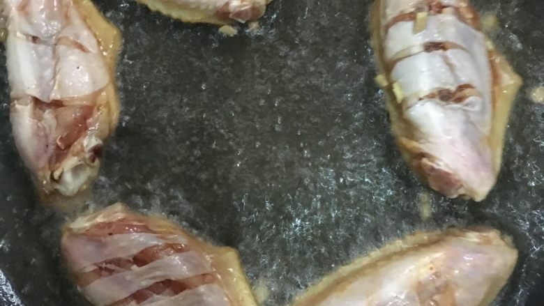 可乐鸡翅,锅里加油烧热，把鸡翅放入煎至两面金黄