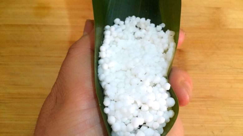 柠味水晶粽,如图左手托住粽叶将粽叶边缘向里收