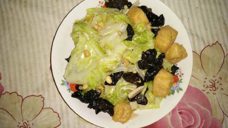 白菜木耳爆豆腐,锅内倒油,爆香蒜片,放入圆白菜木耳油豆腐翻炒,倒入料酒,普宁豆瓣酱,加少许糖继续翻炒后出锅