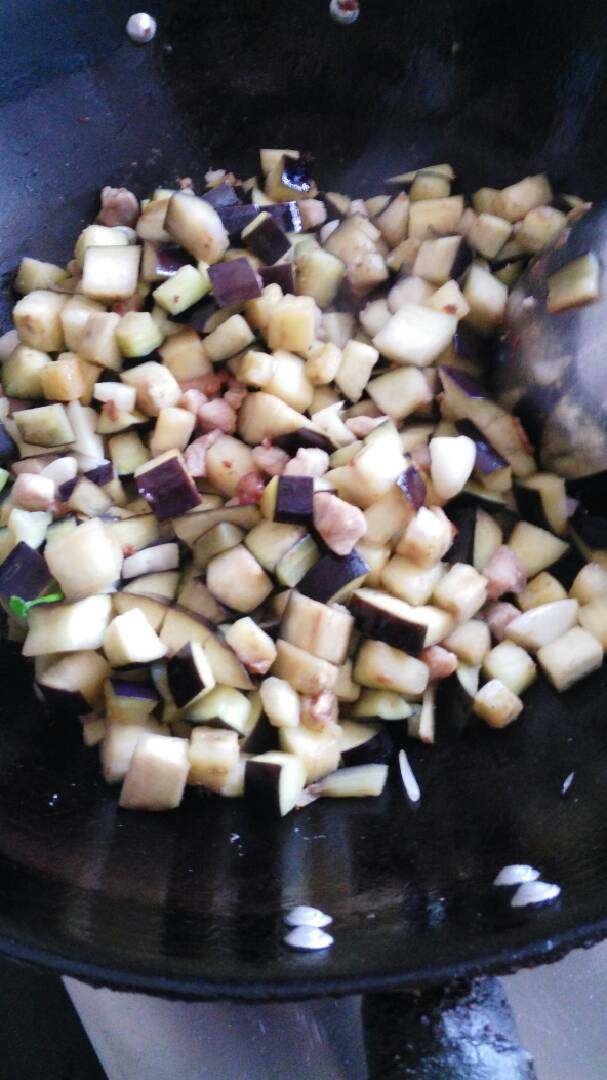 麻酱猪肉茄子凉麺,起锅注油，煸(另1/3)炒五花肉出油，加入腌制好的肉丁煸炒断生，再加入茄子丁，继续煸炒片刻。