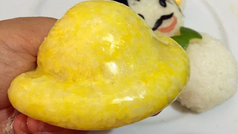 父爱如山,蒸好的南瓜和米饭搅拌均匀称为黄色饭团,取一块黄色饭团利用保鲜膜制作出帽子的形状