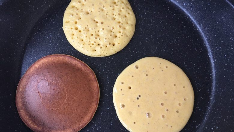 软软奶香玉米饼,平底锅预热,不要放油~舀一勺面糊倒在平底锅中,它会自然摊开变成圆形。最上面那个起泡泡的状态就可以翻面了,火可以小一点,我刚开始火大了翻面不及时就会像下面那个上色太重了。
