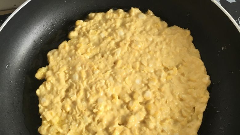 玉米鸡蛋饼,把搅拌过的玉米粒倒入锅内,摊平