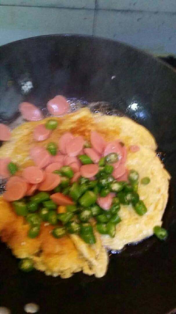 鸡蛋炒火腿,几分钟后倒进火腿肠和青辣椒，接着炒