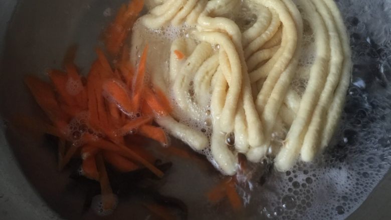 手工鸭蛋面条,开煮,煸香红萝卜和黑木耳,加入开水,放入面条