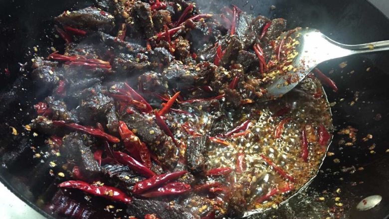 麻辣牛肉干,再把分开的油倒入锅里(平时炒菜的量),放入牛肉小抄,不断的翻炒(中小火),待油沸腾时放入方块糖,放入剪好的干辣椒(先放一部分先入味辣味,喜欢吃辣椒的同志们可以后面在加量)。