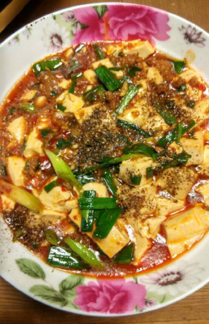 家常麻婆豆腐,热锅下菜油冒烟，下牛肉法炒至变色发白，郫县豆办，炒.至出红油加水下酱油生抽烧开，下豆腐煮开，下香蒜苗煮开两分钟，下水豆粉勾欠。略煮汤浓起锅装盘，趁热再撒上花椒面。