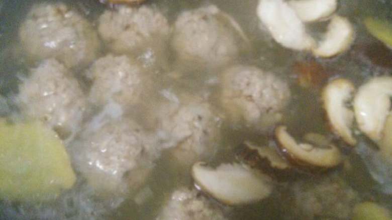 香菇肉丸汤,水再次烧开后加入香菇片,姜片,再盖上锅盖煮。