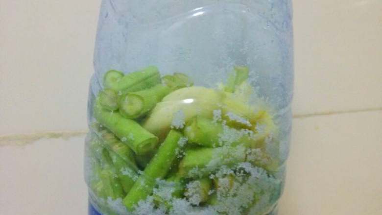 一个空瓶子做出来的美味#酸豆角#,瓶子提前洗净凉干水气,再把豆角和大蒜放入,加2勺盐。