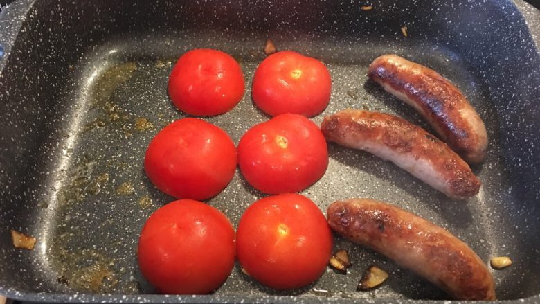 三人周末早餐,洋葱炒熟后盛出，放入些黄油，西红柿放入时切面向下煎。煎到一半时要往下按压，确保煎的彻底。最后连同肉肠一起盛出准备开吃！