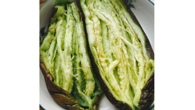 美味烤茄子,将茄子从微波炉取出,竖着切开平铺于盘中。