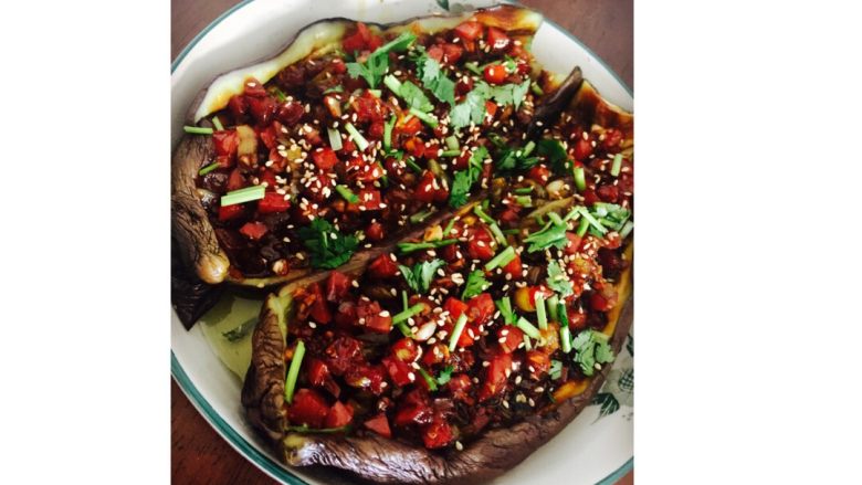 美味烤茄子,锅中全部食材浇在茄子上,盘子再次入微波炉加热2分钟。取出表面撒少许白芝麻香菜即可。