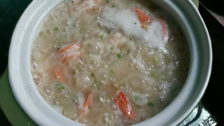 鲜虾瘦肉粥,开大火,先将虾下粥,稍稍搅拌,再将肉和葱香菜一起放入粥里,搅拌使肉不结块抱团,放盐和酱油调味就可以关火了。