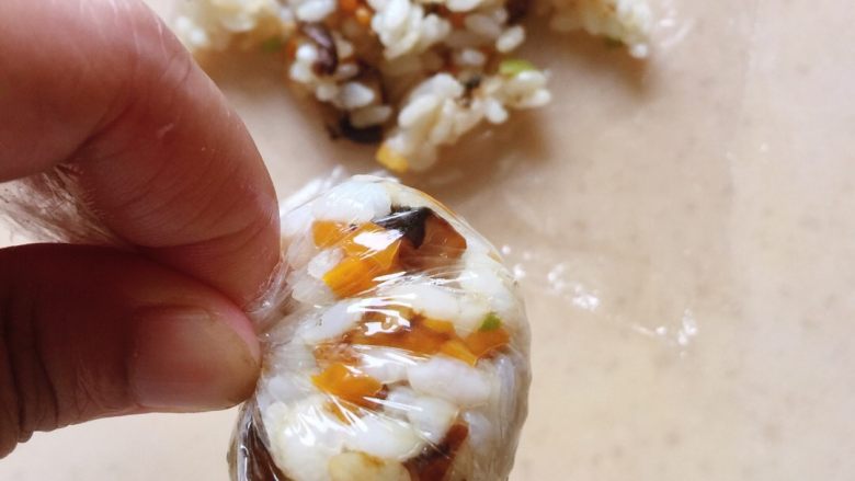 芝士饭团,保鲜膜按图中那样卷紧,弄成圆球状就好了,因为饭刚刚烧好,还有点烫,所以芝士到时还是会容易融化的。