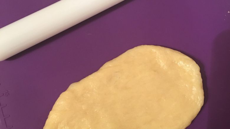 葱花肉松面包,把发酵好的面团分成5份,取其中一份面团擀成长舌形,卷起来