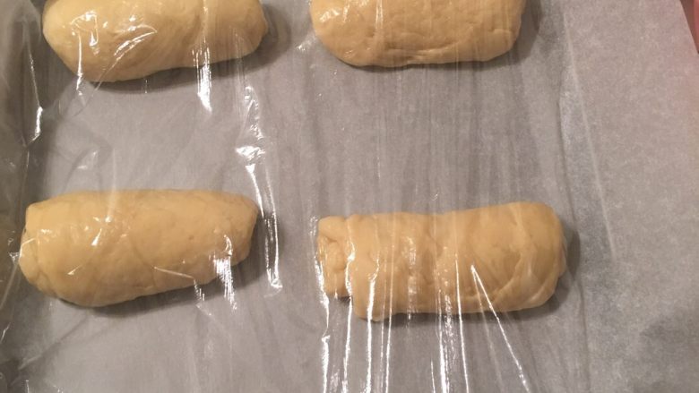 葱花肉松面包,将卷好的面团放在烤盘上,盖上保鲜膜进行第二次发酵10分钟