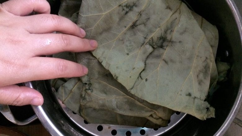黑椒糯米鸡翅,将糯米塞入去骨的鸡翅中 荷叶垫底 鸡翅摆放好 将剩下的糯米铺在鸡翅上 包好荷叶