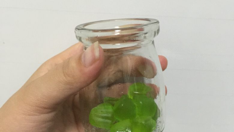 水果味布丁(超简单),将QQ糖倒入玻璃瓶中。我用的是大包QQ糖,70克,分在了3个100ml的玻璃瓶里,要是平时喝水的茶杯,分两杯就行。
