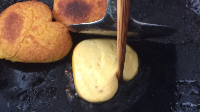 爱心南瓜饼,开慢火煎,下锅时用锅铲与筷子再定形一下,煎一面再小心翻一面煎,再用锅铲与筷子定形,后慢慢煎,变黄了就熟了