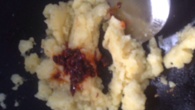土豆泥(三味道),倒少许油,放土豆泥加辣椒酱,混合均匀炒至起少许锅巴。提示:我没买葱,放些葱花炒更香。