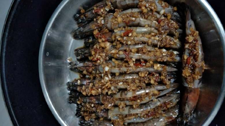 蒜蓉蒸虾,用剪刀把虾须剪掉,剪开虾背部把虾线去掉洗干净,用刀再在背部继续切深一点,把虾装在碟子里摆好备用。