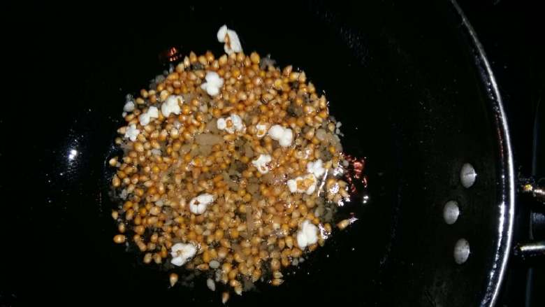 爆玉米花,待有第一颗玉米花爆了,立即盖上锅盖,端在手里不停的摇晃,注意不要离开火焰太远不停地摇晃。