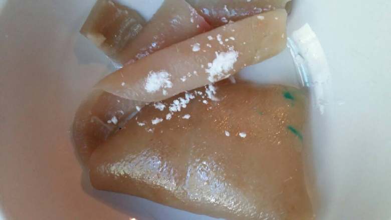 水晶猪皮冻,用刀刮尽油部分和皮毛,用一点点食用碱粉和白醋用温开水搓洗几遍,可以减少剩于的油脂。
