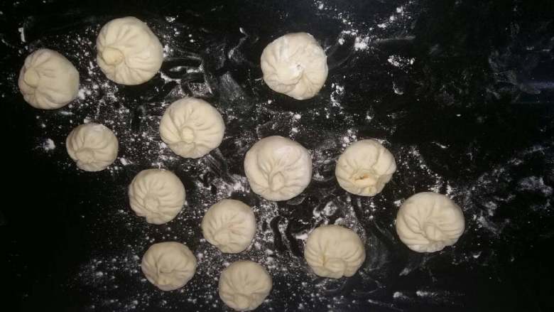 菜包子(萝卜豆腐),小剂子摁扁,中间厚一点,边上薄一点,装入馅料打褶封口。依次全部做好。