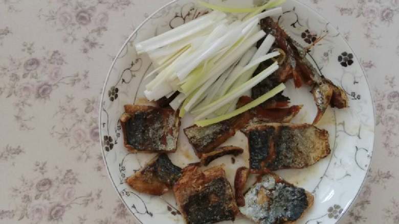 香煎咸鲅鱼,再切些葱丝,摆入盘中。