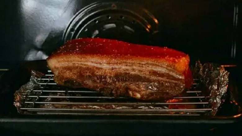 脆皮烧肉,将猪肉从烤箱中取出,将多余的盐粒去掉,将五花肉放在烤架上,再烤10—15分钟左右。