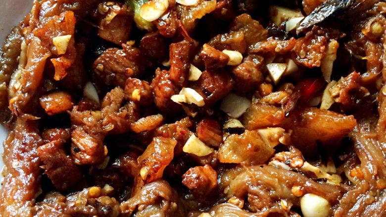 铁锅茄子,热锅热油爆香蒜,加红椒丝炒熟肉丁后捞起备用。
下面仿铁板茄子步骤开工
把前面烫软的茄子刨开,里外刷油后,用锅中剩油小火,注意是小火哦,在铁锅中煎茄子。边煎边用菜铲压压,茄子吃油八分左右后,在上面浇白酒,陈醋,香油,酱油各一菜铲。焖煮一会后下肉丁,盐,蒜末翻炒后起锅。