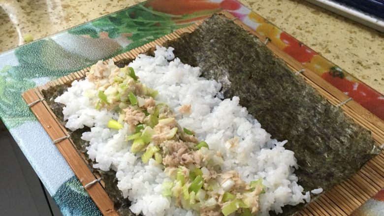 寿司组合,加入鱼肉和大葱混合物50克,卷起即成