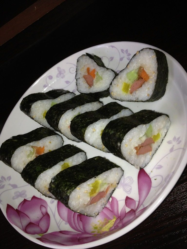 紫菜卷饭,最后是卷的部分.先把模具备好.放进紫菜片.加少量米饭平均压好.再把材料放进去…最后加米饭压实.再把紫菜片压好…用寿司刀切断.点着芥末跟酱油…