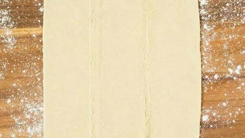 草莓松塔酥,将<a style='color:red;display:inline-block;' href='/shicai/ 550'>高筋面粉</a>、<a style='color:red;display:inline-block;' href='/shicai/ 548'>低筋面粉</a>、盐和<a style='color:red;display:inline-block;' href='/shicai/ 869'>白砂糖</a>一起放入盆中,加<a style='color:red;display:inline-block;' href='/shicai/ 156925'>水</a>揉捏均匀成团,用保鲜膜密封放冰箱冷藏半小时。
将冷藏后的面取出,放在案板上擀成方形,然后在面皮中均匀抹上<a style='color:red;display:inline-block;' href='/shicai/ 887'>黄油</a>,将面皮的四角向中间折,再擀成方形,重复折叠四次,放入冰箱冷藏一个小时后取出。
一小时后将面皮取出,按照前面的方法再折两次,擀成长方形。