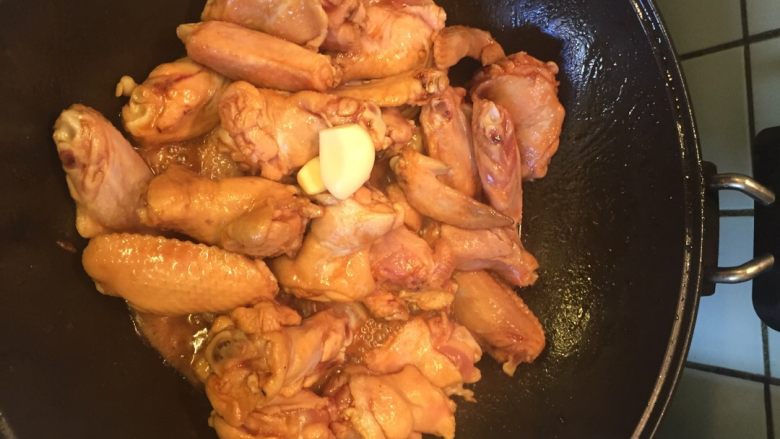 红烧鸡翅,加入大蒜，盖上锅盖并闷一下，再翻炒