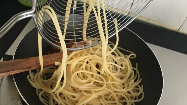 自制肉丸和油浸小番茄的肉丸红酱意面,意面煮的差不多了就捞出加入橄榄油拌匀,意面酱关火,把意面放入平底锅一起翻炒,这时候其实相当于搅拌。