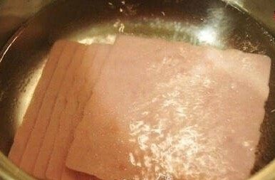 鸡蛋吐司 小热狗,将火腿切片放入锅中油煎一下!煎成外焦里嫩即可。如果不想太油,可以将火腿切片放入开水锅中过下水!