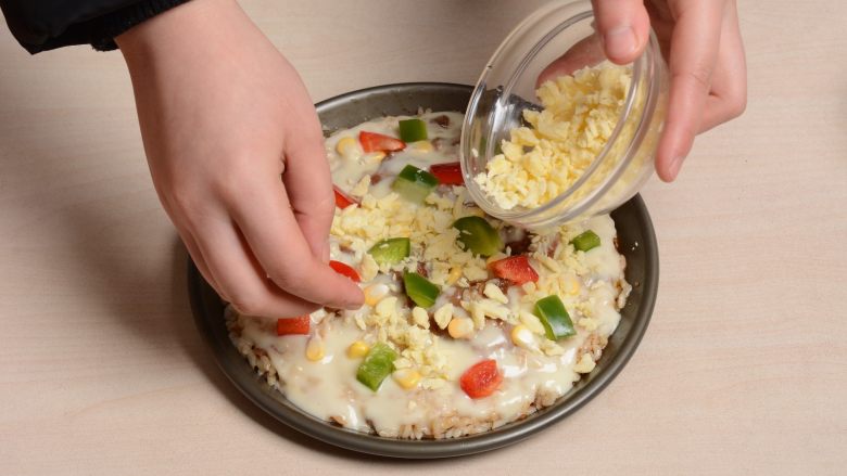 麻辣猪软骨铁盘焗饭,依次撒上青红椒玉米粒后在表面覆盖上芝士