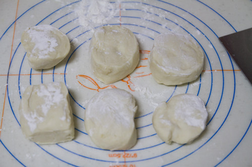 韭菜盒子,案板上洒面粉,醒好的面团放在案板上,揉一揉,搓成条,切成6个小面团,在馅料里加盐拌匀。