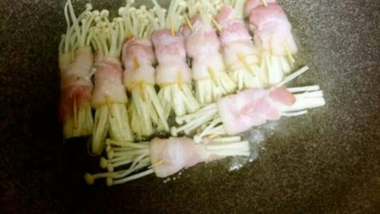 培根金针菇,把锅内放入一点油，放入卷好的金针菇(不粘锅的可以不放油)