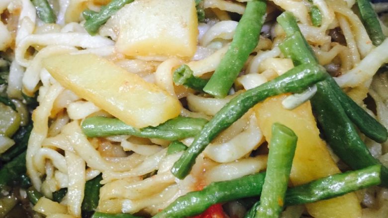 豆角土豆焖面,中火加热八分钟掀开锅盖，用手指沾凉水均匀弹到面上，一边弹凉水一边用筷子搅拌开，最后把菜和散开的面条搅拌均匀