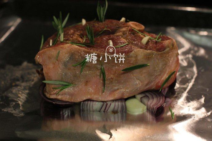 【迷迭香烤羊腿】中西混搭版,将洋葱和剩余的蒜片铺在锡纸上,再把羊腿架在洋葱片上