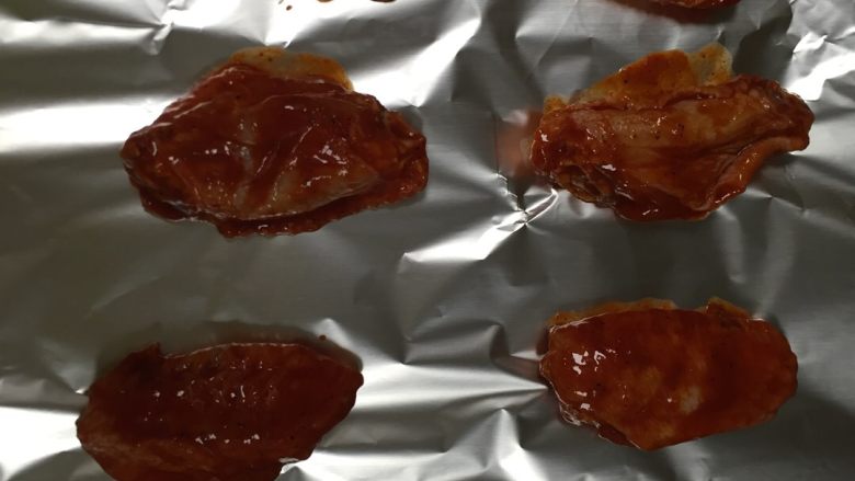 奥尔良烤鸡翅,把烤盘铺上锡纸,烤箱180度上火预热5分钟,放入烤箱烤15分钟,中途注意翻面,不用涂油,因为鸡皮本身就会出油,也可中途在表面涂少量玉米油,会更有光泽。