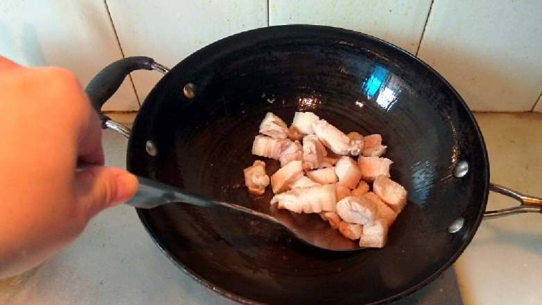 红烧五花肉,锅里放油适量,油八成热下五花肉翻炒。